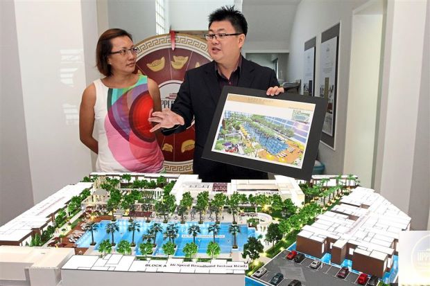 Tiew (right) showing the key features of the landscape design based on the apartment project’s model at Upper EastTiger Lane sales gallery while Chuah looks on.