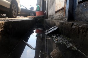A drain clogged with oil grease and sludge found behind a shoplot.