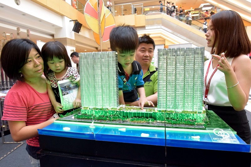 Rapt attention: Zeon Properties marketing executive Iris Wooi (right) talking to Cheah Chee Phon and wife Teoh Hui Chiu as their son Zheng Xuan takes a much closer look at the display model, at the StarProperty.my Fair 2016 in Sunway Carnival Mall, Seberang Jaya.