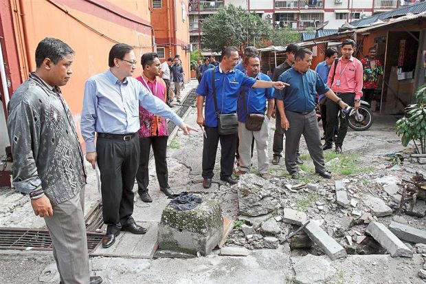 Chew (left) accompanied by residents looking at the broken drains during his visit to Taman Ikan Emas.