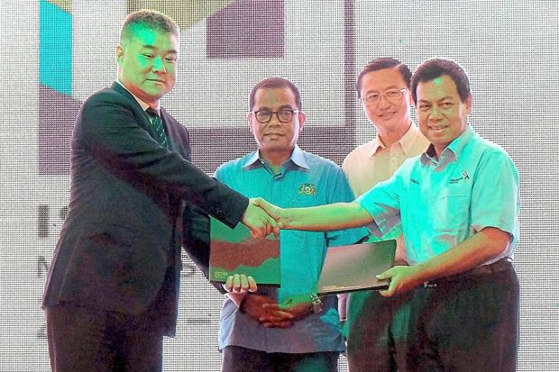 Ismail (right) exchanging documents with Wu (left) to establish the Iskandar Malaysia Greenland Smart City Experimental Centre. Looking on is Mohamed Khaled (second from left).