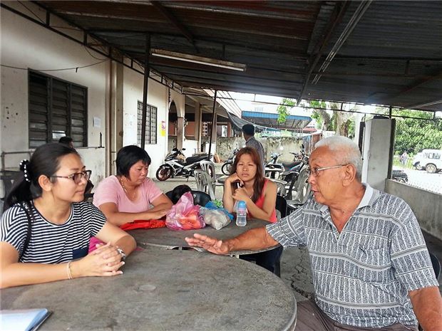 Weng (right) relating the problems of uneven road surfaces and drainage problems to Wai (left).