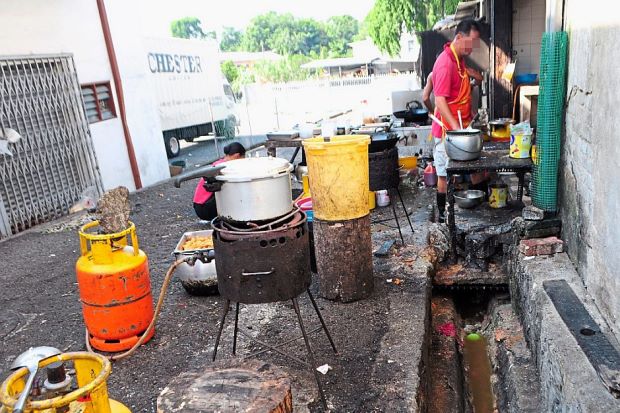 Breaking all the rules: The health department prohibits direct discharge of water from pipes into drains as well as washing plates or preparing food in back lanes. Only restaurants with fat, oil and grease (FOG) traps will be issued licences. This restaurant in Taman Megah, Cheras, however, is still operating as a result of poor enforcement. — GRACE CHEN/The Star