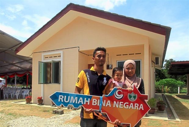 Noradila, her husband Saiful Fazly and their daughter Dhia Anissa Dian, with the mock key of their RM45,000 house built under Risda's scheme.