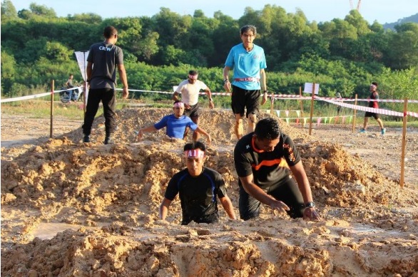 Participants trying to cross over one of the obstacle: Dirty Crossing filled with muddy water.