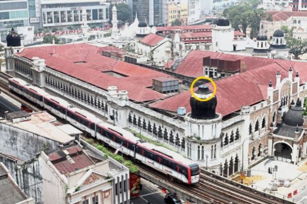Contrast of the old and new: A Light Rail Transit (LRT) passing next to the 108-year-old former Federated Malay States (FMS) Survey Department building. The spire on one of its domes (in yellow circle) collapsed late last year and the rest of the building also appears to be in a poor state. — FAIHAN GHANI/ The Star