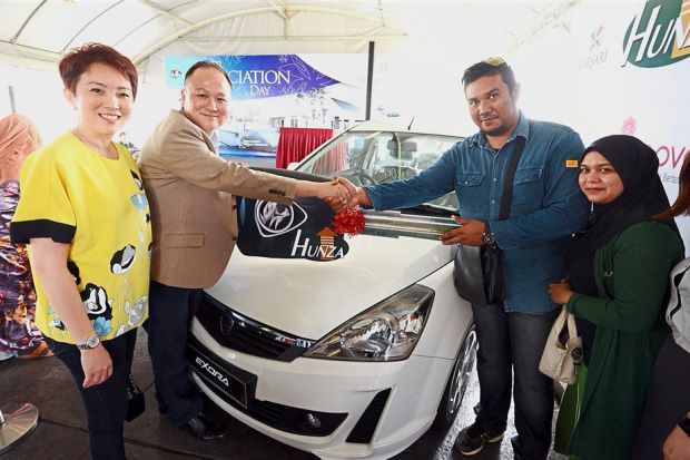 Mohd Faizal (second right), accompanied by his wife Syazana, receiving his new car from Khor and Tan (left).