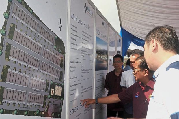 Mohamed Khaled (second from right) looking at the redevelopment plan for Kampung Senibong.