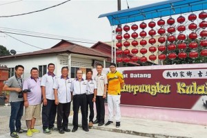 Chen (fourth from left) and other villagers with New Village development officer Chen Woei Jye (second from right) at the village‘s landmark 
