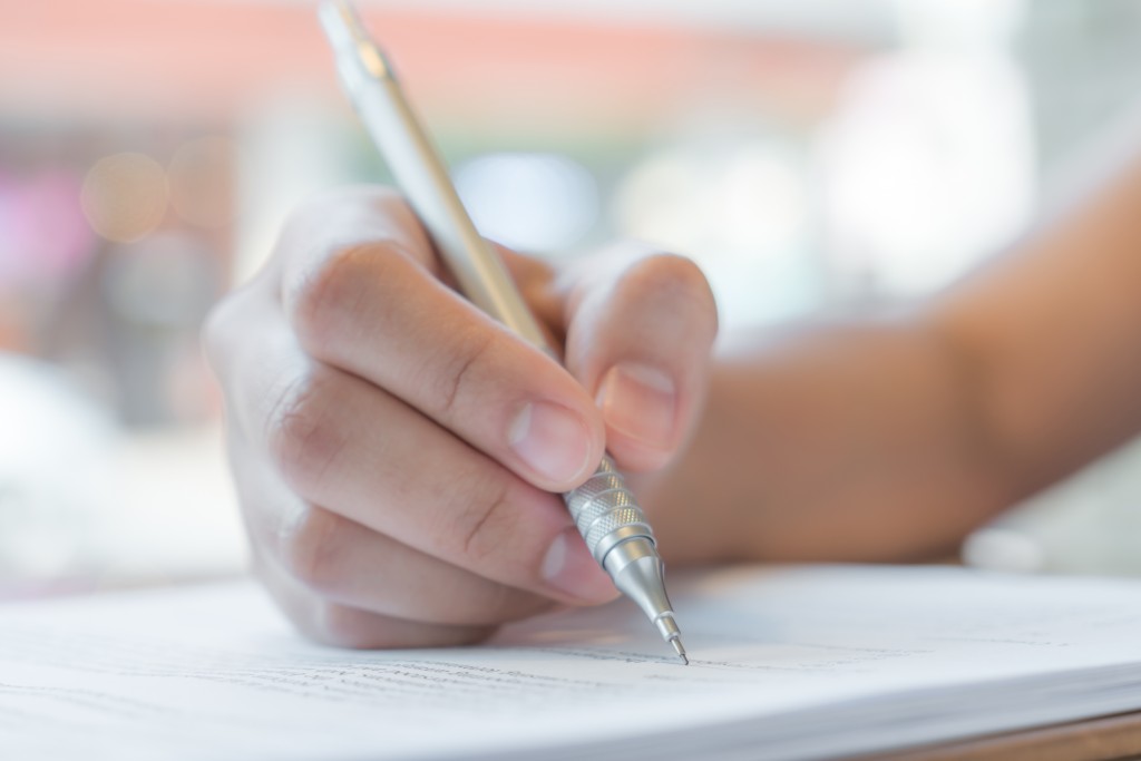 Hand with pen over application form