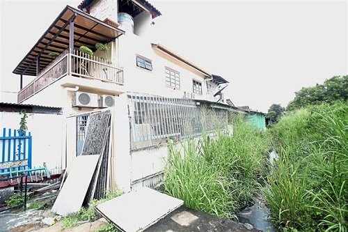 An earth cut drain has not been maintained and is overgrown with lalang.