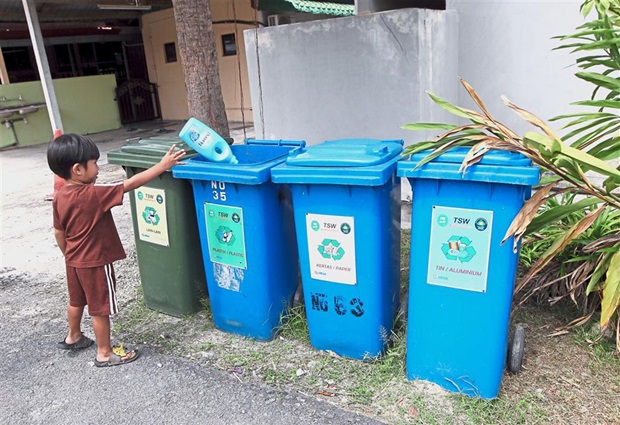 Three-year-old Irash Saad throwing a plastic bottle into the recycling bins placed at the corner of every street in Taman Setia Warisan.