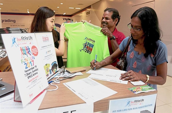 S. Thulasimani, 52, signing up for the Fit For Life Fun Run while her husband K. Mahaligam, 63, looks at the event’s T-shirt.