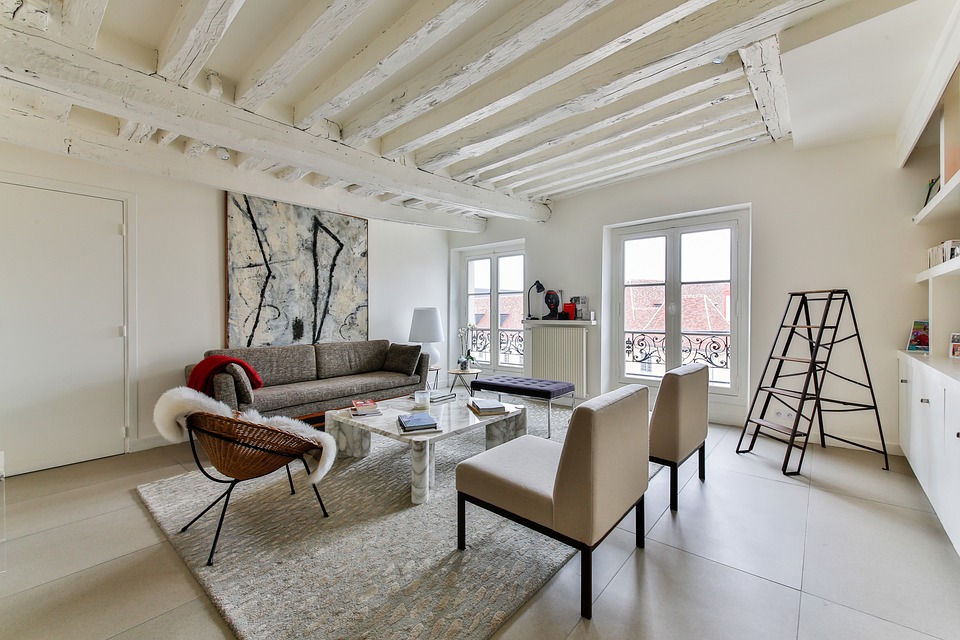 The pale architectural finishes and minimalist furnishings upholstered in accordance with a neutral palette are the hallmarks of Scandinavian style, pictured here with the charming accompaniment of rustic wood beams painted in white.