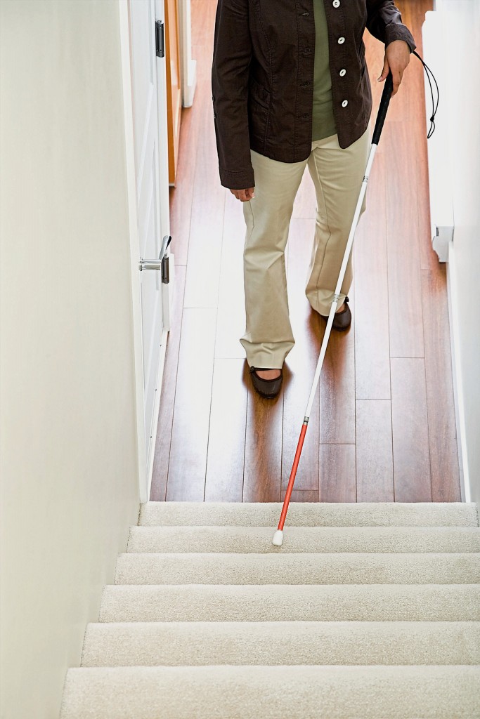 Blind woman using a walking stick on stairway