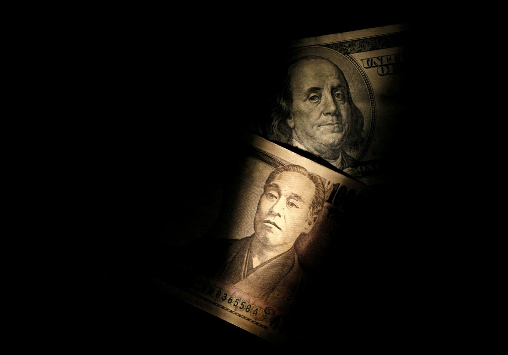 FILE PHOTO: Light is cast on U.S. one-hundred dollar bill next to Japanese 10,000 yen note