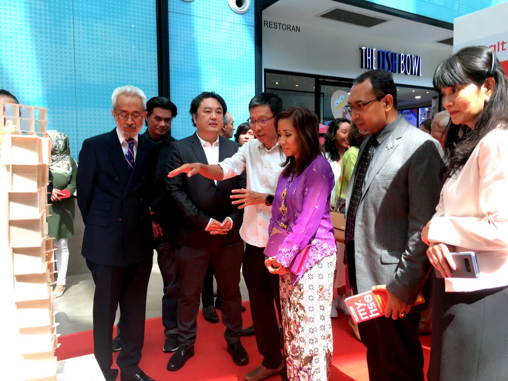 建筑师梅志雄向展览会主礼嘉宾暨雪兰莪州皇室公主东姑札塔莎讲解其公司aLM建筑事务所创作的屋苑概念。前排左起为房屋及地方政府部副部长拿督拉惹卡玛鲁巴林和2018年吉隆坡建筑嘉年华总干事洪志忠；右二为依祖米。