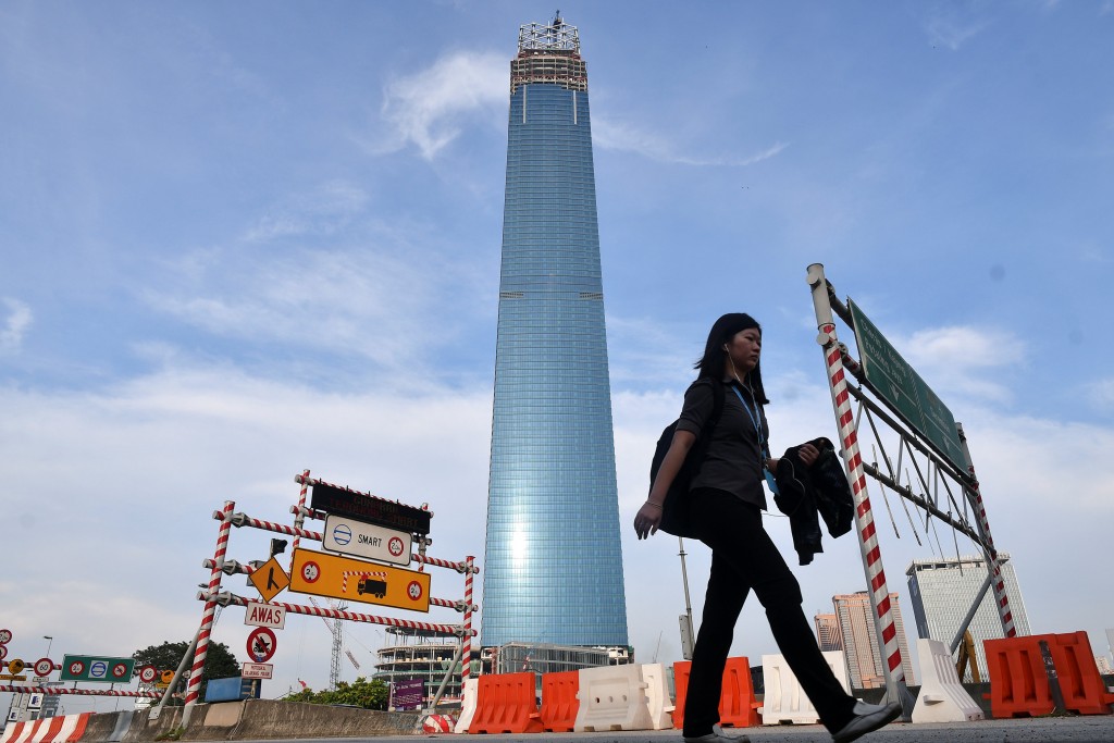 Woman passes the Tun Razak Exchange development in Kuala Lumpur