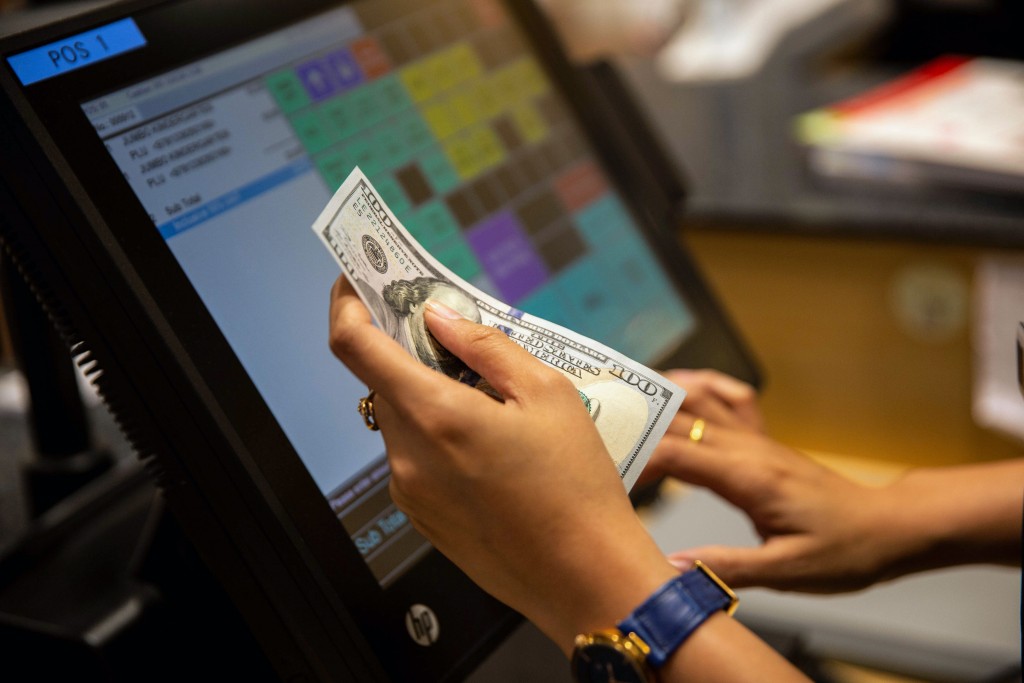 An employee receives payment in U.S dollars at a till in the Kinokuniya Co. book store at the Aeon Mall in Phnom Penh, Cambodia. Photograph: Taylor Weidman/Bloomberg