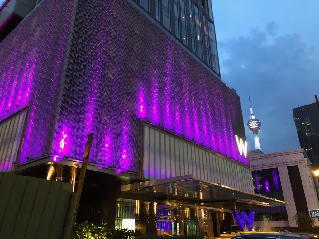 At night, the facade of the W Kuala Lumpur lights up in pink and purple.