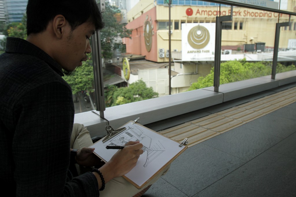 An artist, Zaid Zahuri,  memorialising the façade of Ampang Park from the pedestrian bridge over Jalan Ampang.