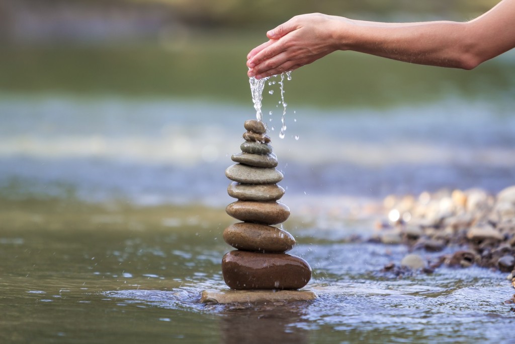Close-up abstract image of woman hand pouring water on rough nat