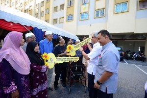 Ahmad Zakiyuddin (second right) and Mohd Salem (right) handing over the mock keys of Selasih Court apartments to villagers of Kampung Mutiara.