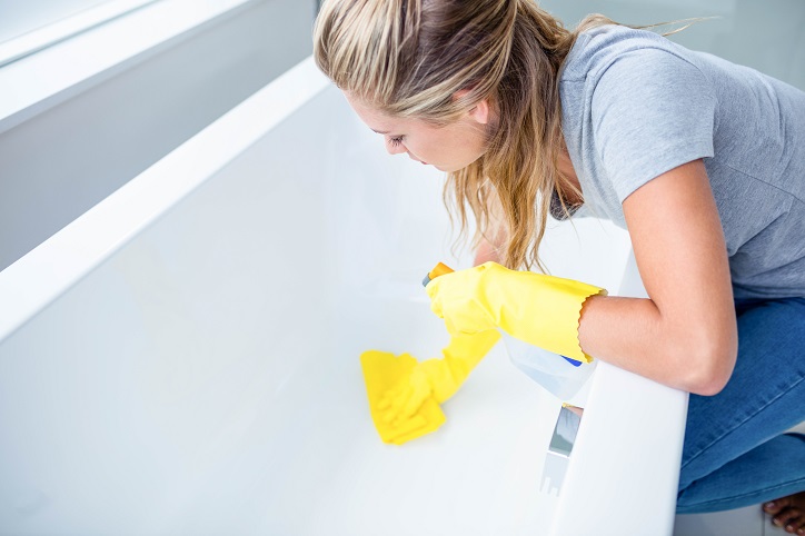 Woman cleaning the bath tub in the bathroom