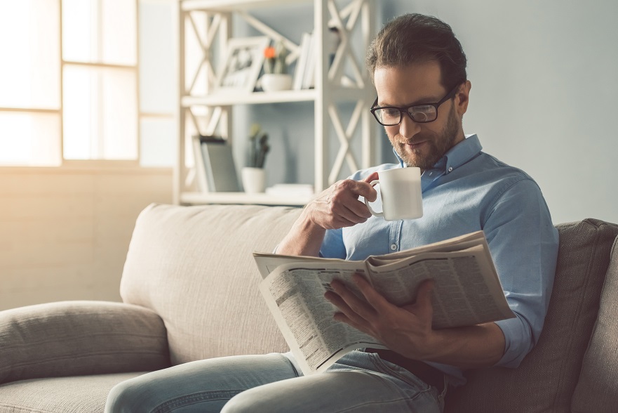 Businessman in eyeglasses is reading a newspaper.