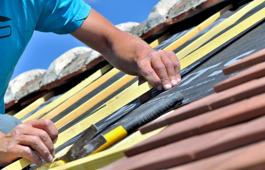 close on the hands of a worker renoving e roof of a house