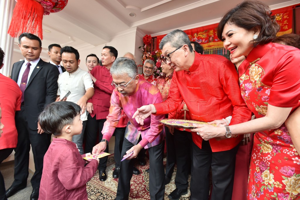 Sultan Abdullah handing out “ang pows” to the children as Hock San looks on.