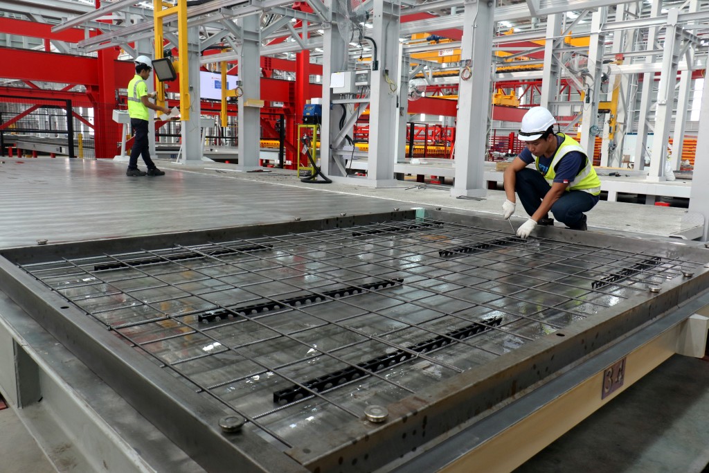 A worker tightens the wire used to tie the reinforcement steel cage before concrete is poured into it to form a wall. This is one of the rare, few manual tasks still being performed at an otherwise heavily automated facility.