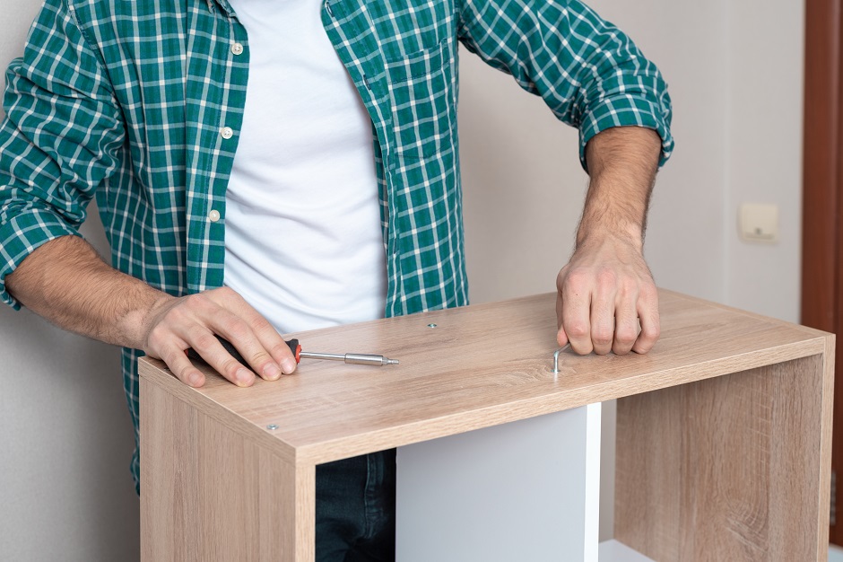 Close-up of a man in a white t-shirt and a plaid shirt twists the bolt with a Z-shaped key, collects furniture