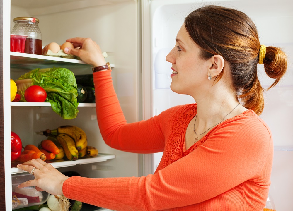 Young housewife near refrigerato