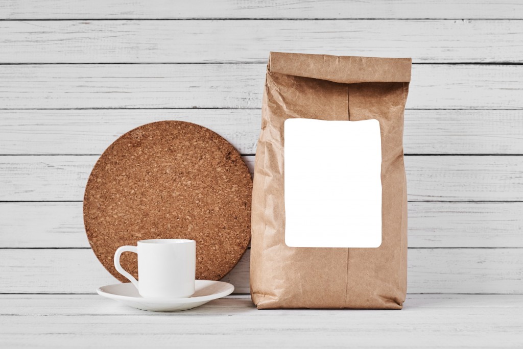 Craft paper bag with copy space and coffee cup on white background