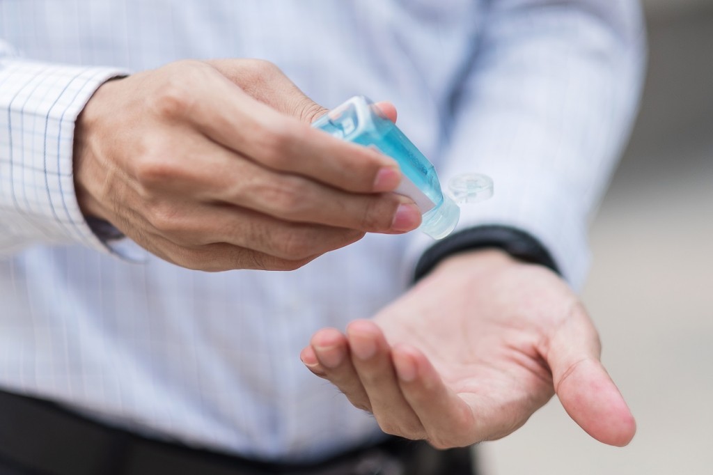 man hands using wash hand sanitizer gel dispenser, against Novel