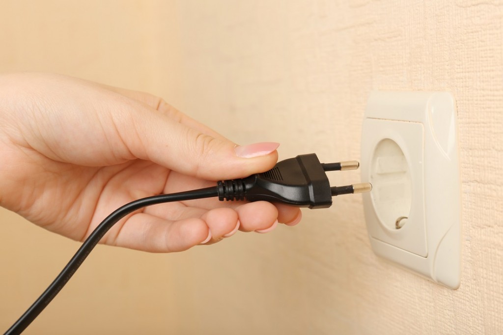 Hand putting plug in electricity socket close up