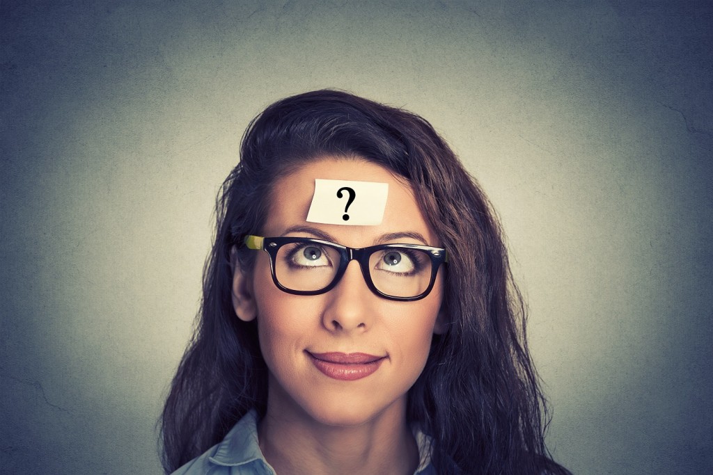 thinking woman with question mark on gray wall background