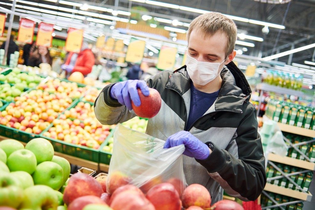 man in mask and protective gloves buying food in shop at coronavirus epidemic