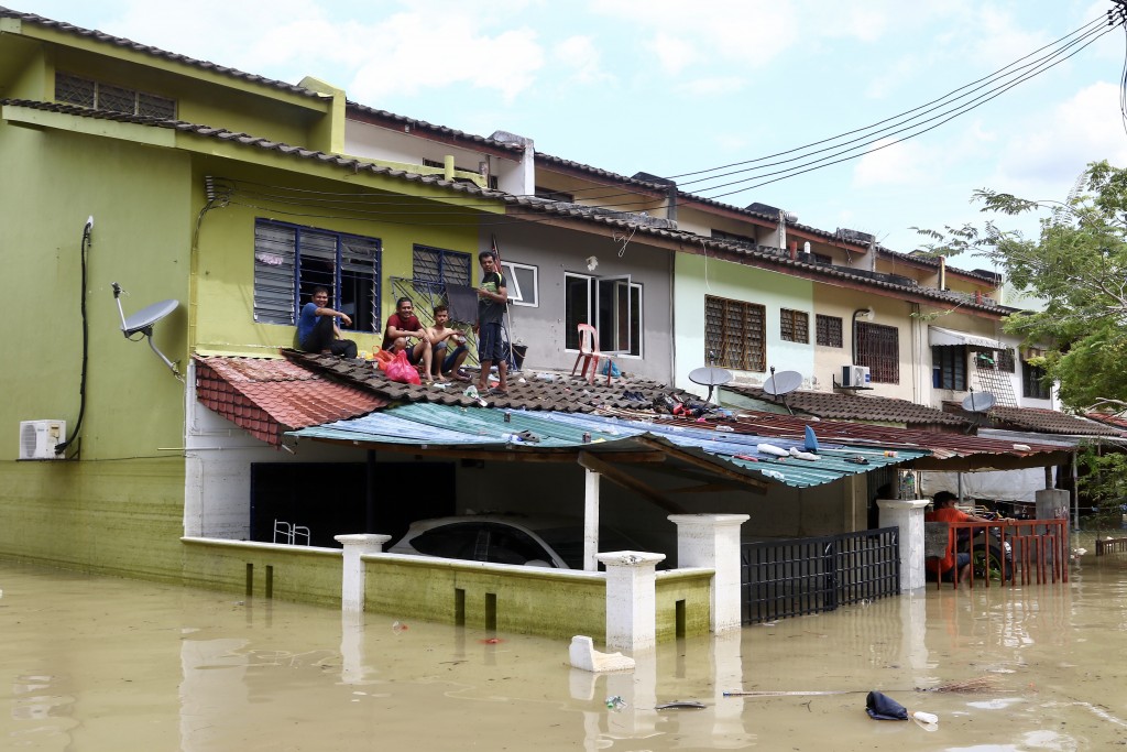 Flood victims in Taman Sri Muda, Shah Alam sitting on top of a roof to escape the deluge.