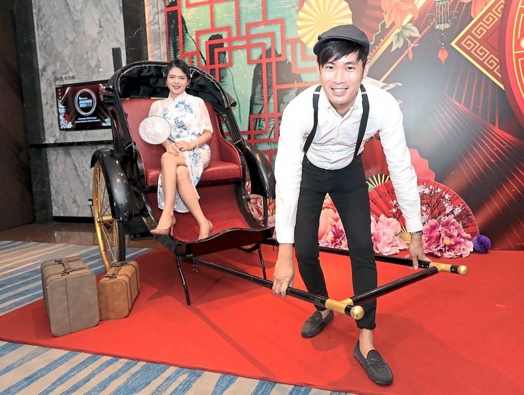 IQI Realty’s Low Han Fung gets ready to pull his colleague Miki Lim on the trishaw.