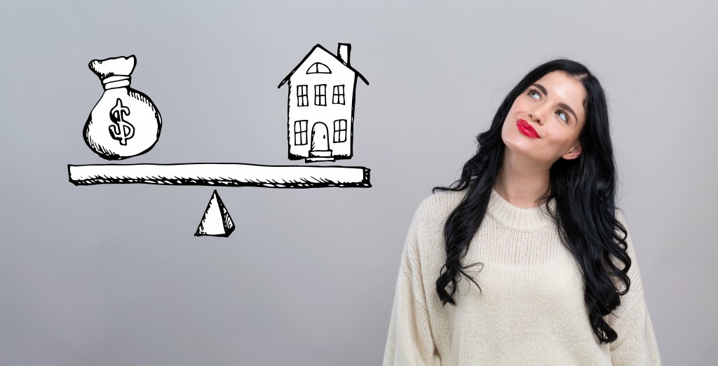 House and money on the scale with happy young woman