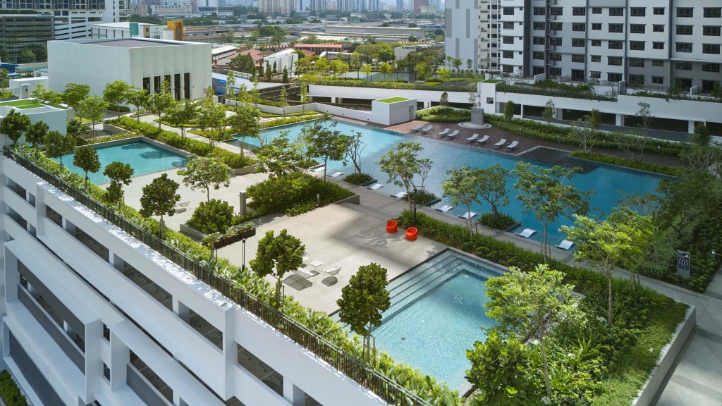 The podium features lush greenery lining the swimming pools, providing shade at the facilities deck.